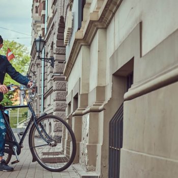 Portrait of a fashionable man in stylish clothes walking with city bicycle on the street. Portrait of a fashionable man in stylish clothes walking with city bicycle on a street.